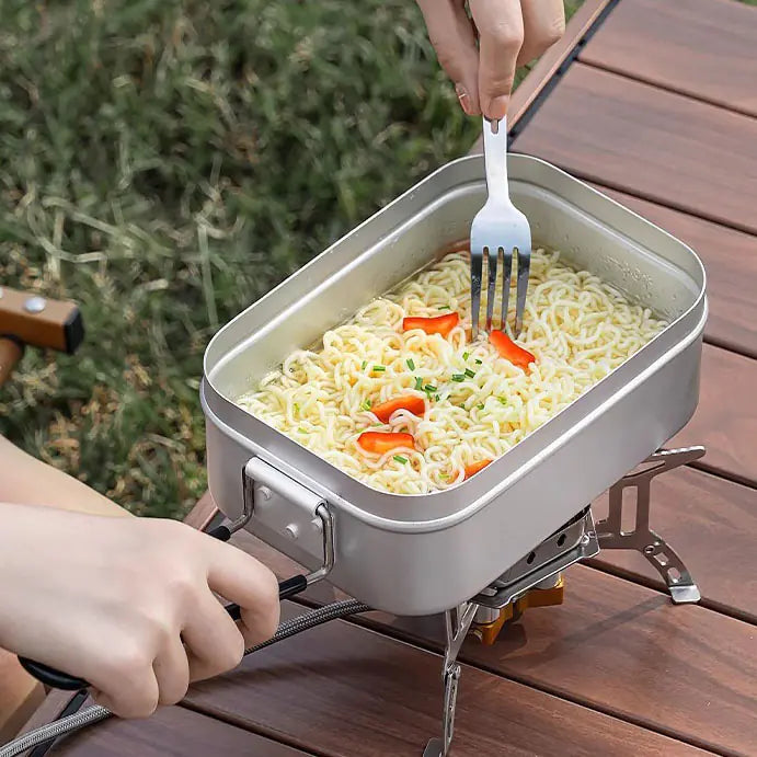 Person cooking instant noodles on a portable stove outdoors