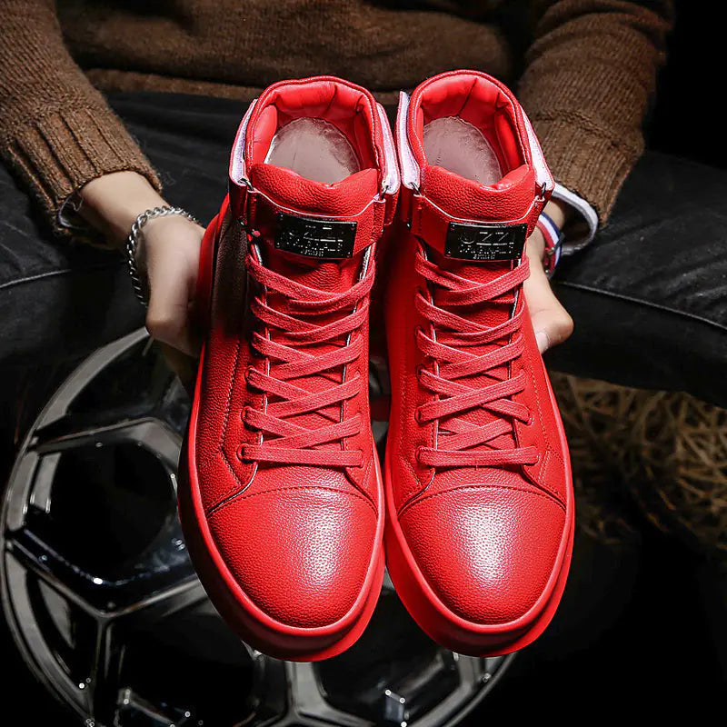 Red high-top sneakers held by a person wearing a brown sweater.