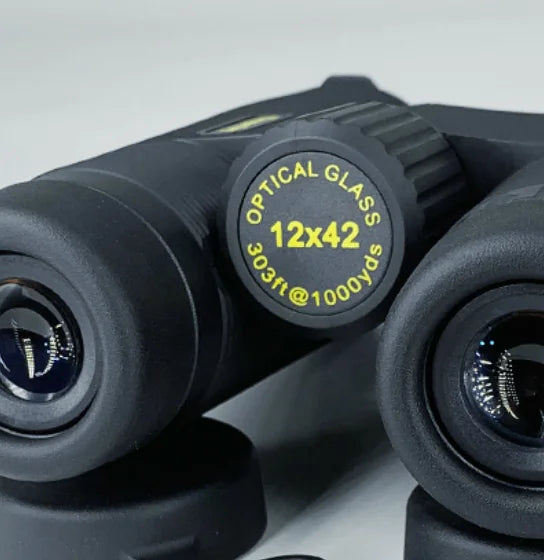 Close-up of a pair of binoculars with focus on the lens and brand name.