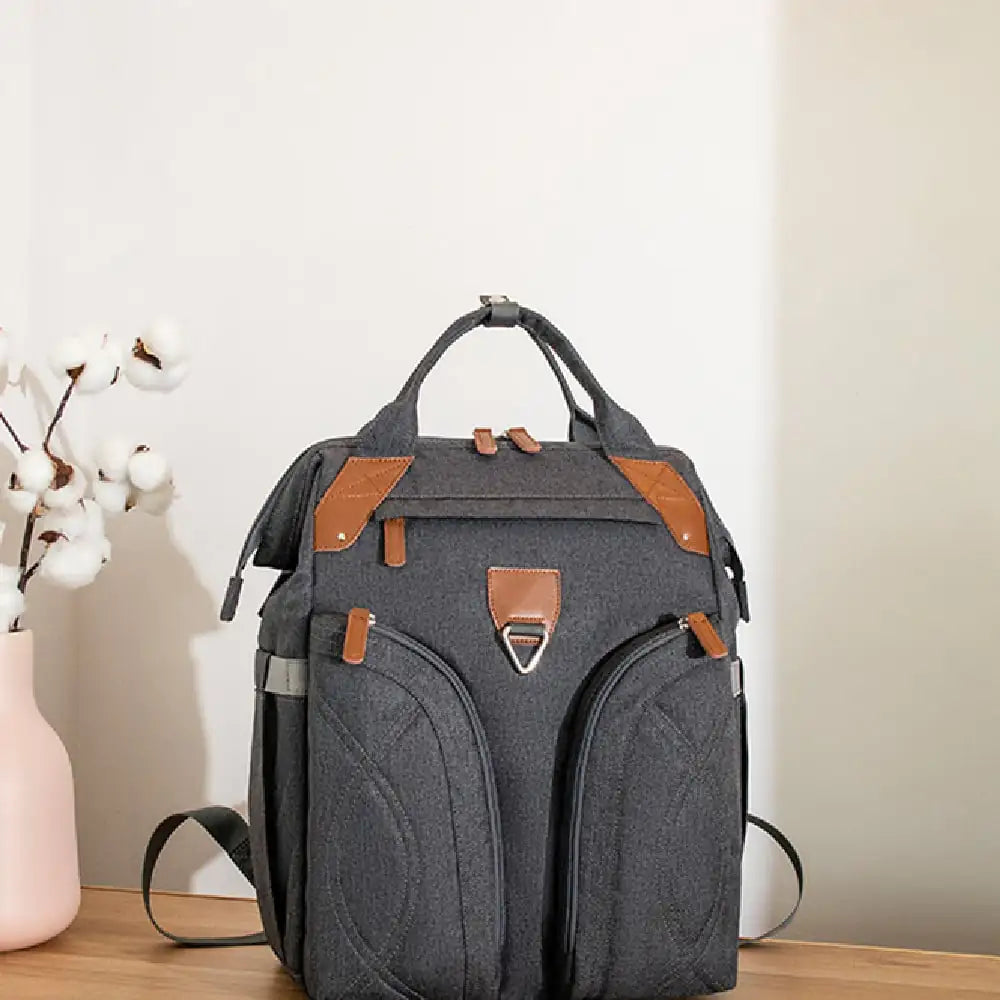 Gray backpack with brown accents on a wooden surface with a light background