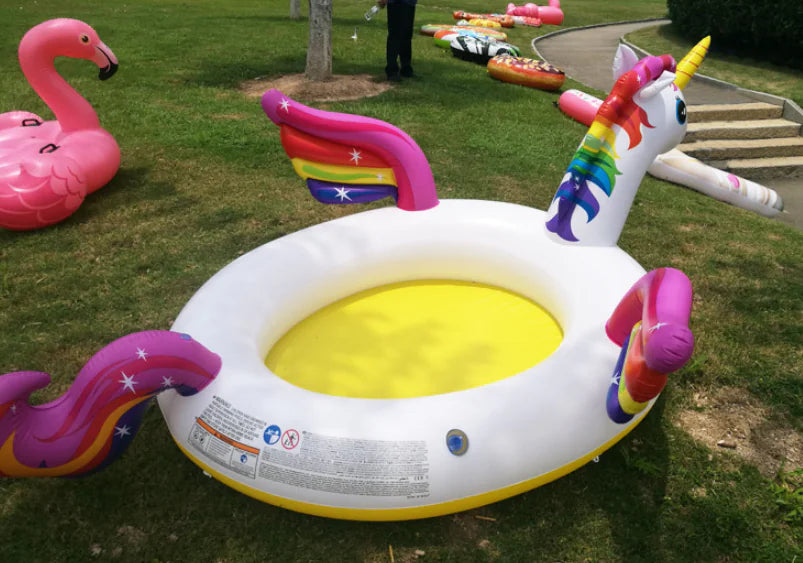 Inflatable unicorn pool on grass with other pool floats in the background