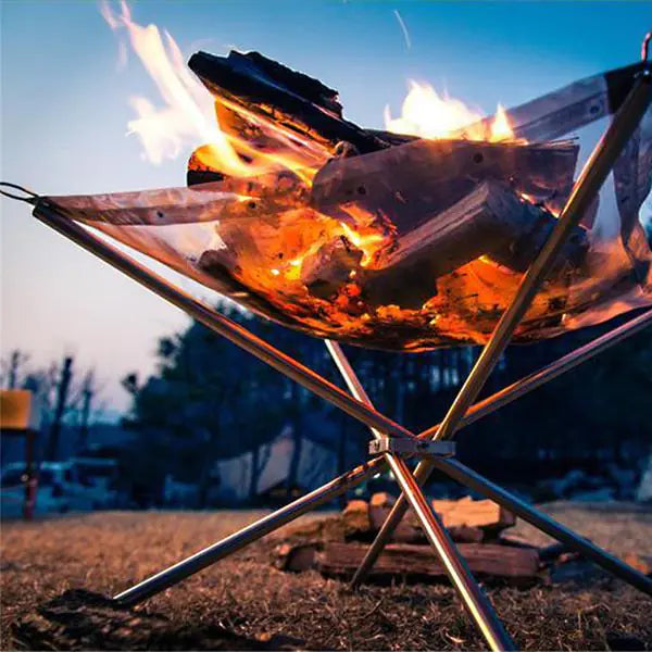 Fire pit with glowing embers and flames on a metal stand outdoors.