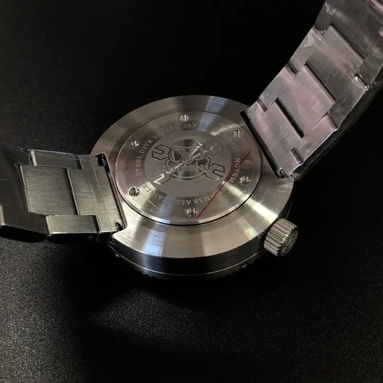 Close-up of a stainless steel diving watch showing back of it with visible brand logo on a black background