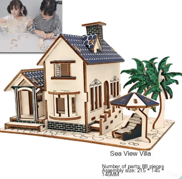 Wooden model of a sea view villa with palm tree and lounge chair, children playing with puzzle pieces in the background.