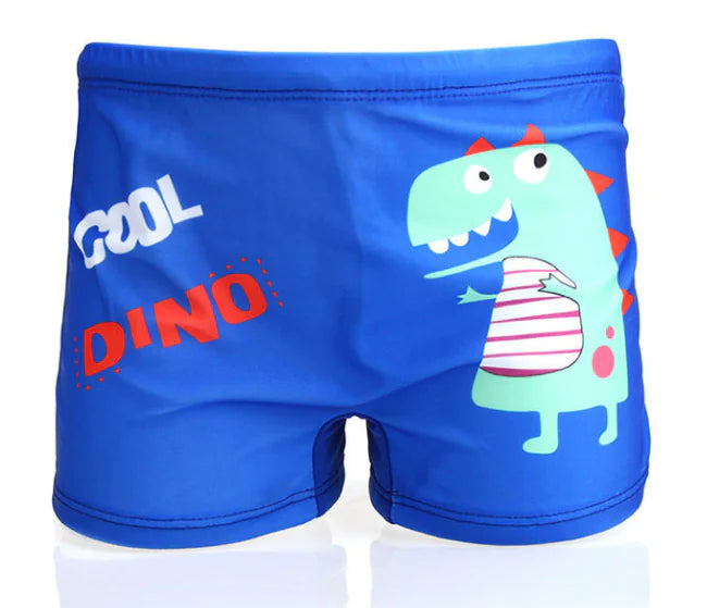 Blue children's swim shorts with a dinosaur design and 'Cool Dino' text on a white background