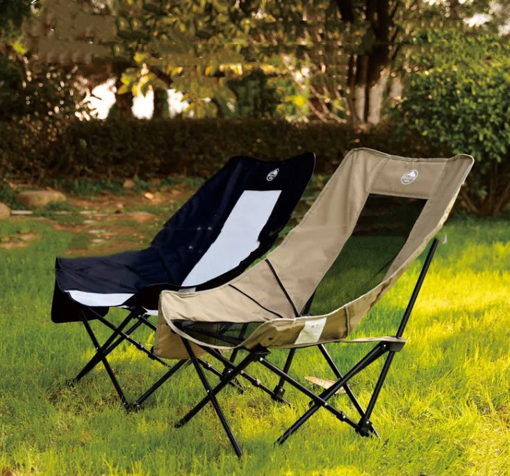 Two folding chairs, one black and one beige, on a grassy outdoor area.