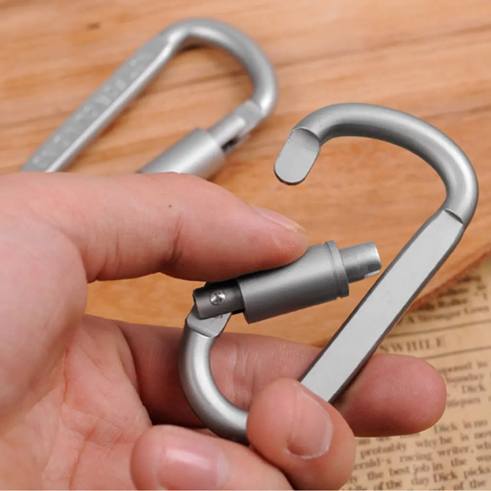 Metal carabiner with multiple hooks held by a hand on a wooden surface.
