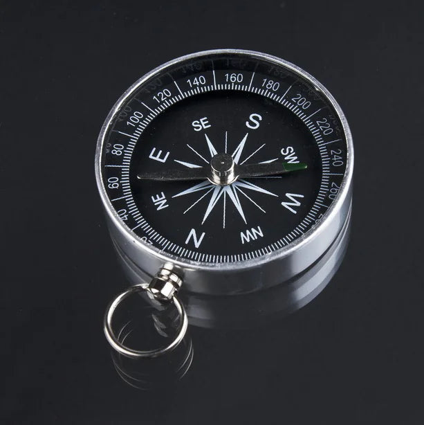 Compass with black dial and silver casing on a dark background