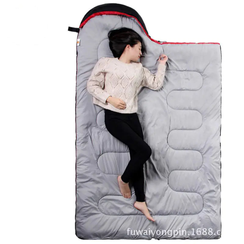 Person lying in a gray sleeping bag on a white background