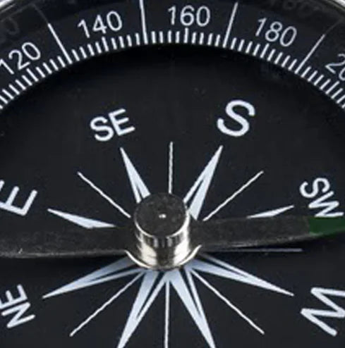Close-up of a compass with the dial and directional markings