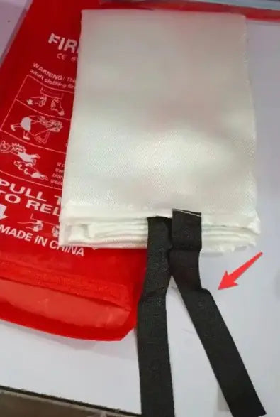Fire blanket with black strap on a red fire extinguisher background