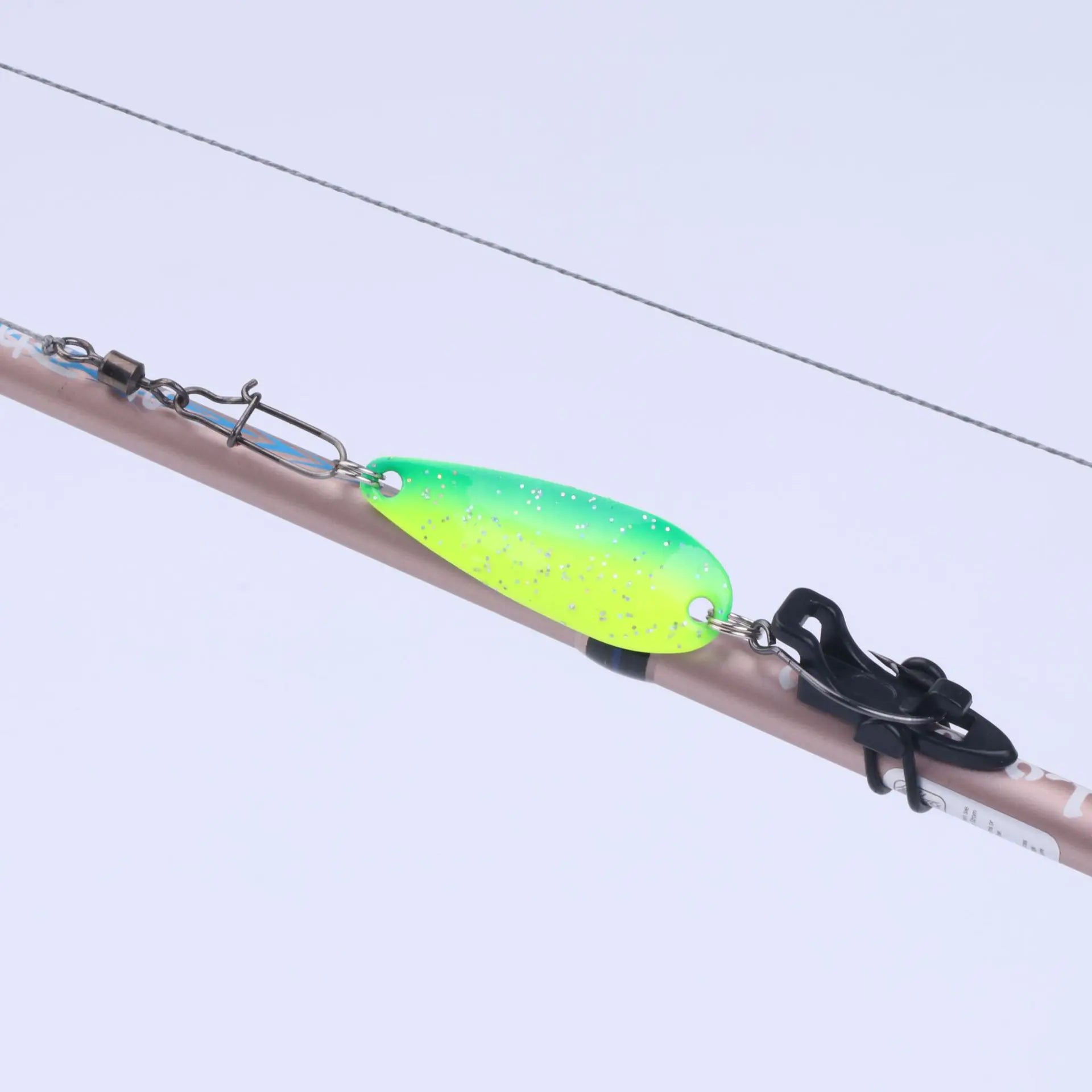 Fishing rod with a green and yellow lure on a light gray background