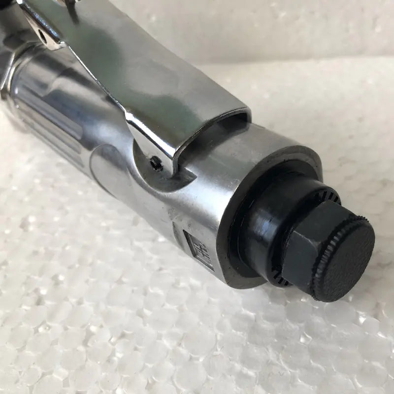 Close-up of a metal tool with a black knob on a textured white background