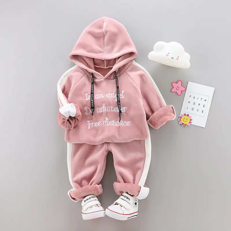 Pink children's hoodie and pants set on a gray background with decorative items.