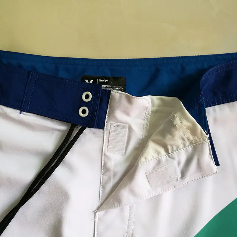 Close-up of a waistband of men's board shorts with velcro closure and a Hurley label on a white background
