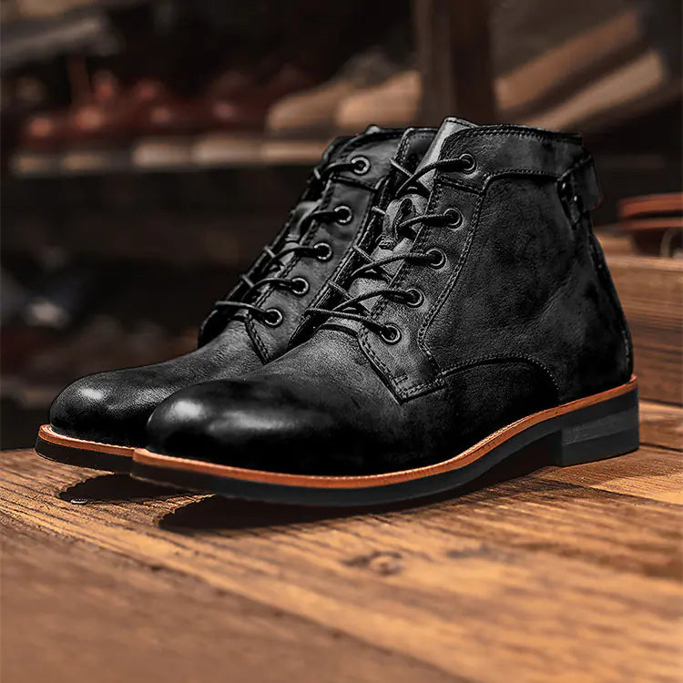 Men's Blackleather laceup ankle boots on a wooden surface with blurred shelves in the background