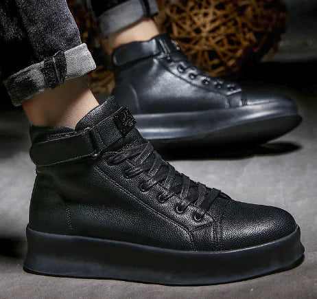 Black high-top sneakers worn with rolled-up jeans on a dark background
