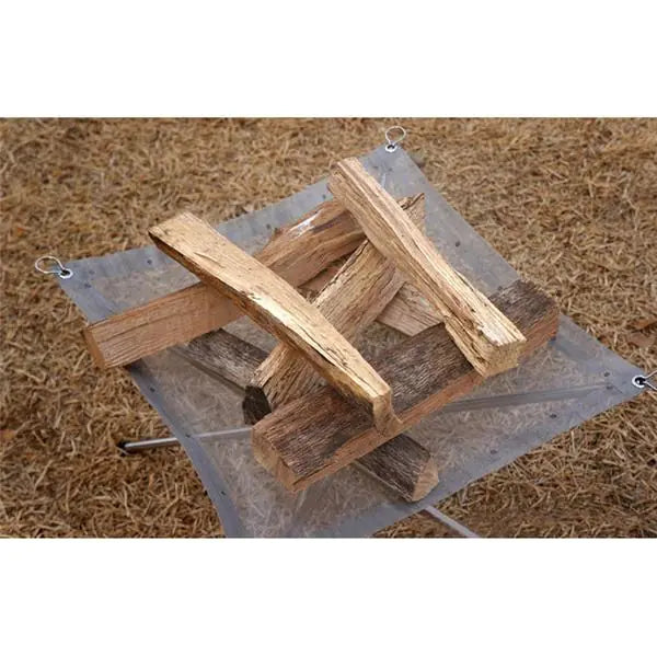  firewood on a metal fire pit grate with a brown mulch background